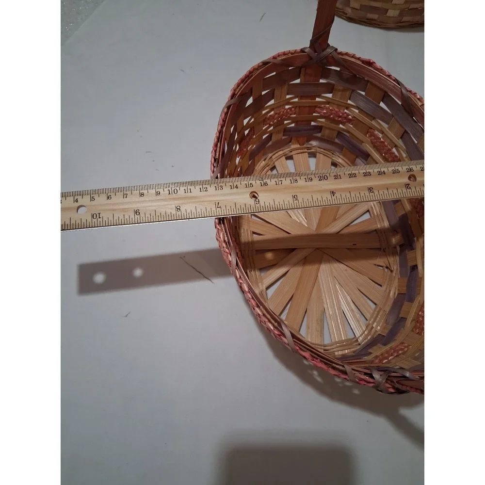 Two vintage woven bamboo baskets with tall‎ handles and pink accenting.